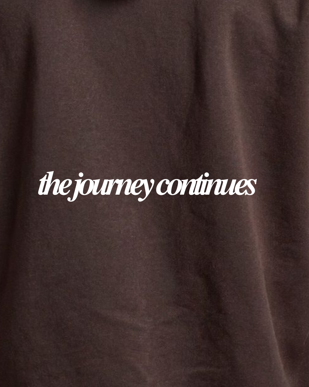 Close-up of a dark brown textured fabric with the phrase 'the journey continues' printed in white script across the center.